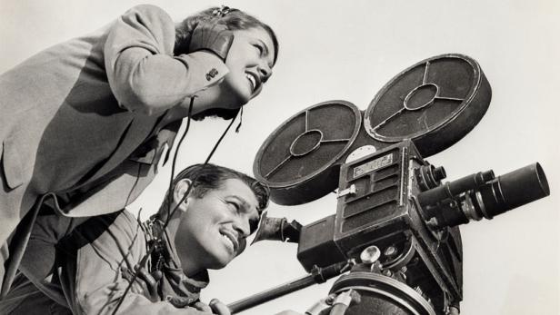 Clark Gable und eine Frau arbeiten mit einer Filmkamera.