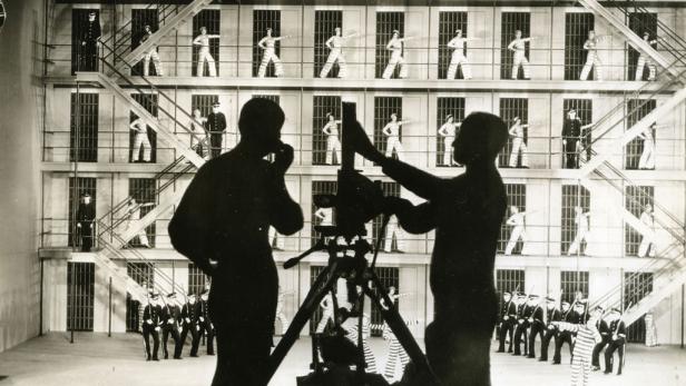 Eine Filmszene mit Gefängniswärtern und Gefangenen, gefilmt von einem Kamerateam.