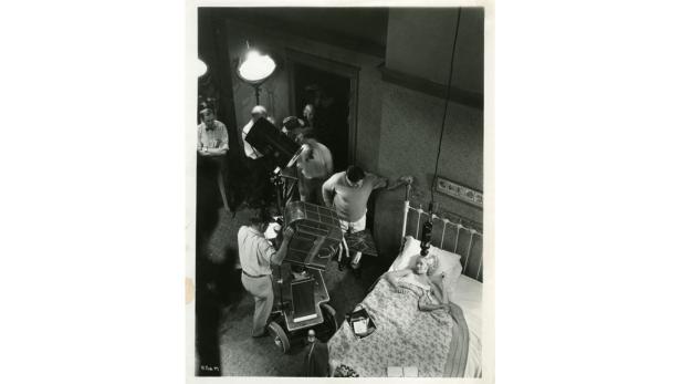 Marilyn Monroe liegt während Dreharbeiten in einem Bett.