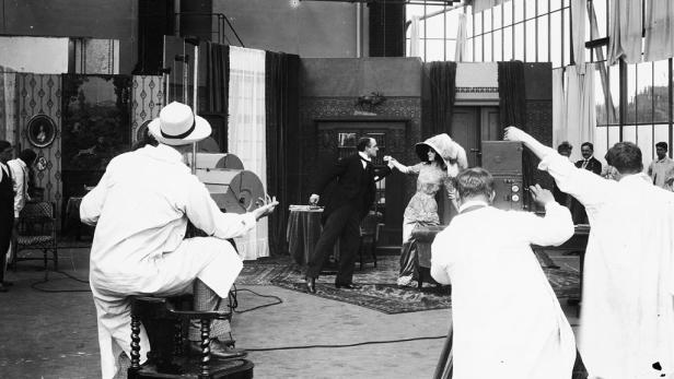 Eine Filmszene mit Schauspielern und Filmcrew in einem Studio.