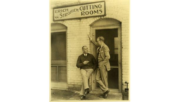 Zwei Männer stehen vor einem Gebäude mit der Aufschrift „Erich von Stroheim Cutting Rooms“.