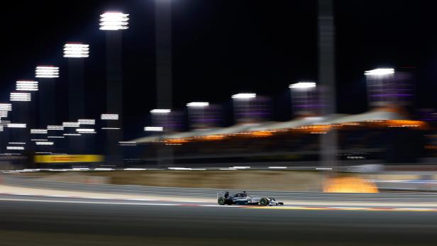 Ein Formel-1-Wagen rast nachts auf einer beleuchteten Rennstrecke.
