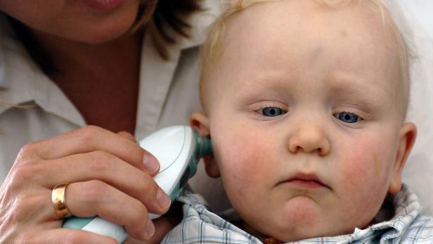 Einem Baby wird mit einem Infrarot-Ohrthermometer die Temperatur gemessen.
