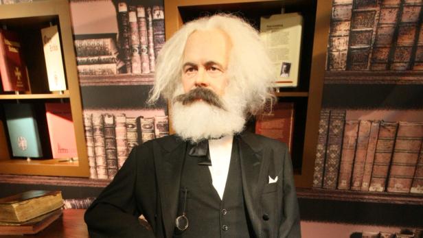 Eine Wachsfigur von Karl Marx vor einem Bücherregal.