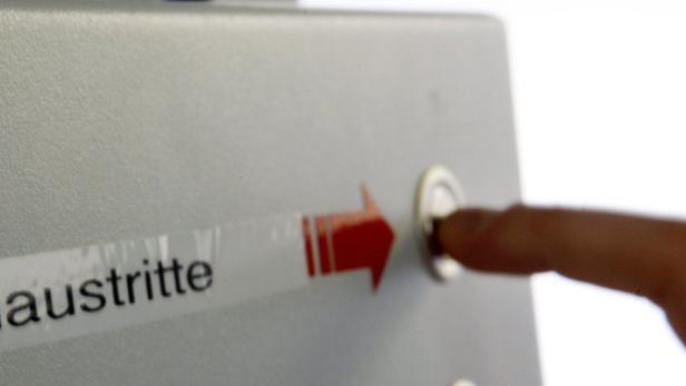 Ein Finger drückt einen Knopf neben einem Schild mit der Aufschrift „Haustritte“.