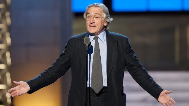 Robert De Niro spricht auf einer Bühne in ein Mikrofon.