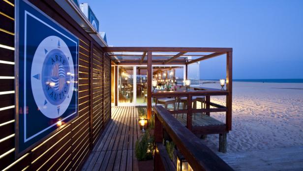 Ein Restaurant mit dem Namen „Arte Náutica“ an einem Strand bei Dämmerung.