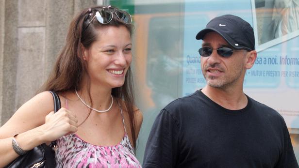 Eine lächelnde Frau und ein Mann mit Sonnenbrille stehen nebeneinander.