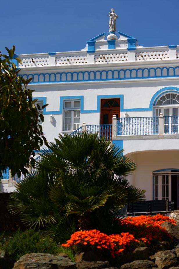 Ein weißes Gebäude mit blauen Akzenten und einer Statue auf dem Dach.