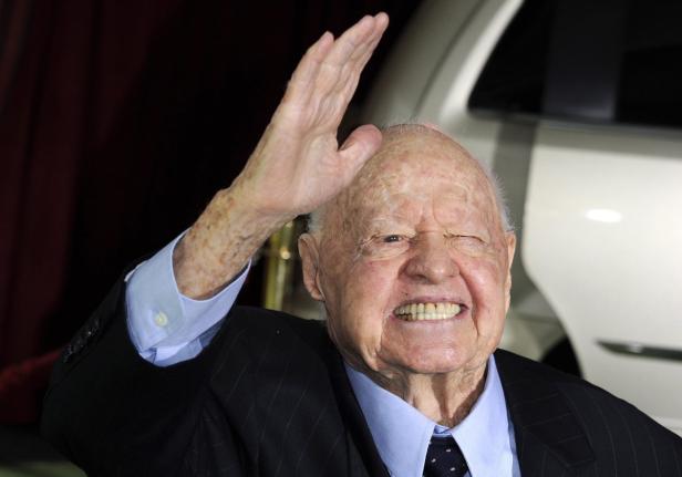 Mickey Rooney winkt mit erhobener Hand in die Kamera.