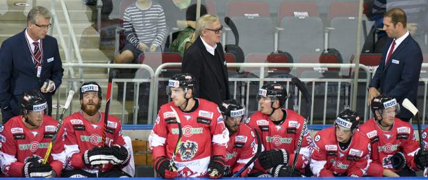 Eine Gruppe von Eishockeyspielern in rot-weißen Trikots sitzt auf der Bank.
