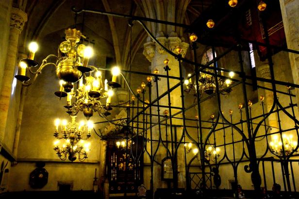 Mehrere Kronleuchter beleuchten den Innenraum einer Synagoge.