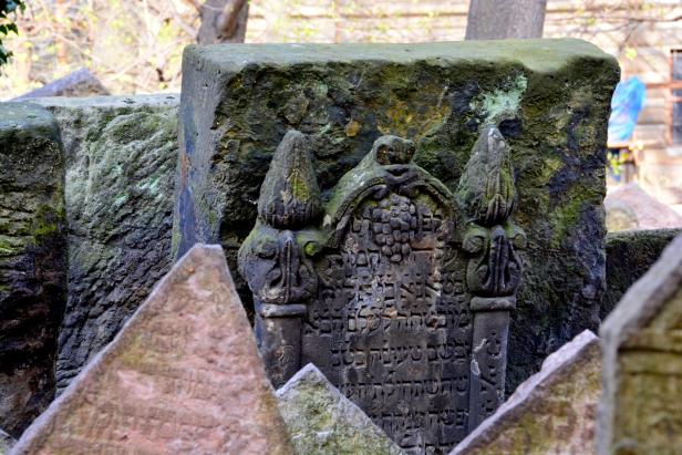 Ein alter jüdischer Grabstein mit hebräischen Inschriften und Moosbewuchs.