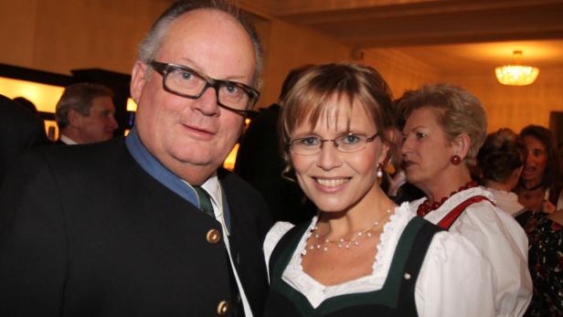 Ein Mann im Trachtenanzug und eine Frau im Dirndl posieren für ein Foto.