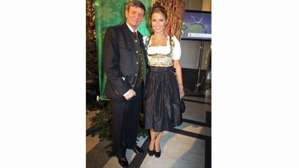Ein Mann im Trachtenanzug und eine Frau im Dirndl posieren für ein Foto.