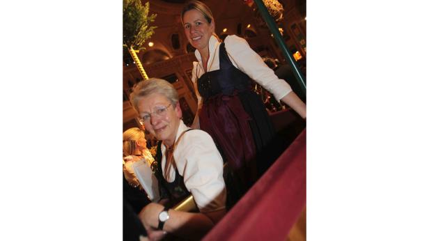 Zwei Frauen in Dirndl sitzen in einem Theater oder Opernhaus.