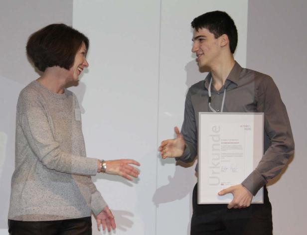 Ein junger Mann erhält eine Urkunde von einer Frau.