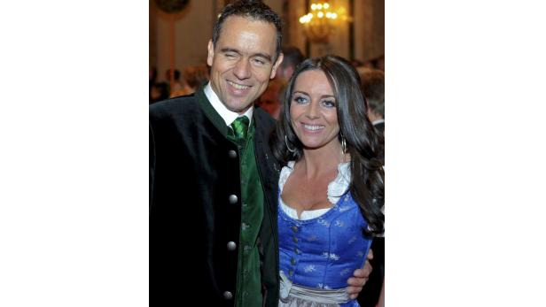Ein Mann in Tracht und eine Frau im Dirndl posieren für ein Foto.