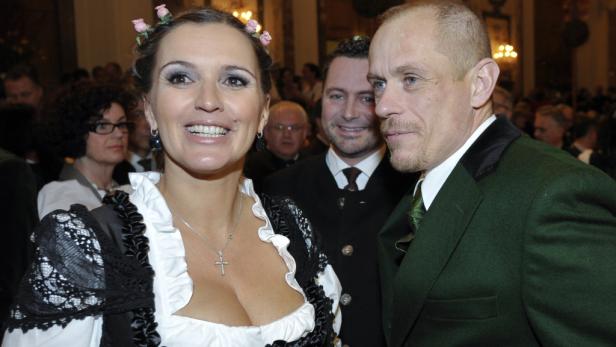 Eine Frau im Dirndl und ein Mann im Trachtenanzug posieren für ein Foto.