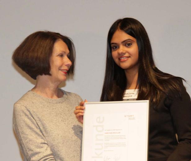 Eine Frau überreicht Harjivan Bhullar eine Urkunde.