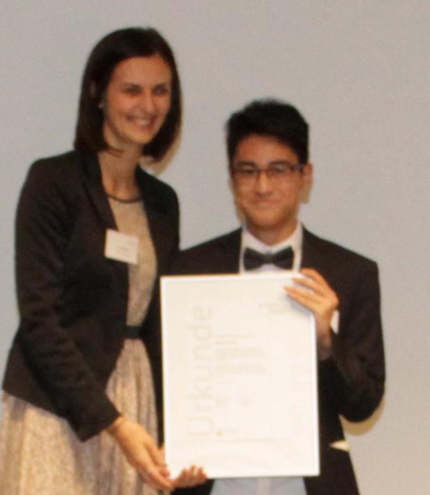 Ein junger Mann nimmt eine Urkunde von einer Frau entgegen.