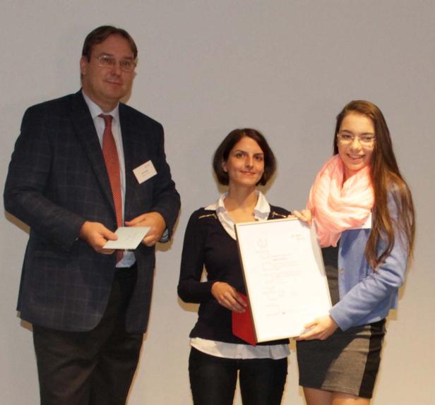 Eine junge Frau erhält eine Urkunde von zwei Personen.