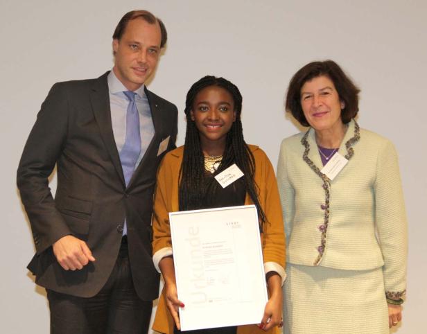 Eine junge Frau hält eine Urkunde zwischen zwei Personen.