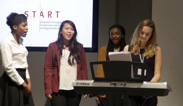 Vier junge Frauen stehen vor einem Yamaha-Keyboard und singen.