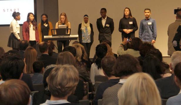 Eine Gruppe junger Leute steht auf einer Bühne vor einem Publikum.