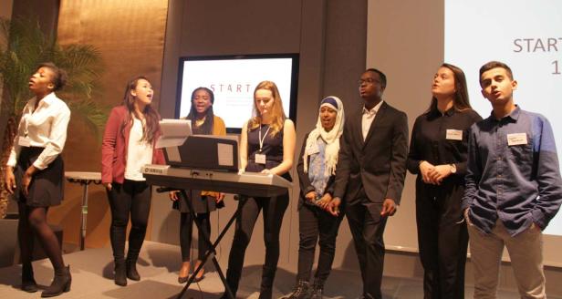 Eine Gruppe junger Leute singt und spielt Keyboard auf einer Bühne.