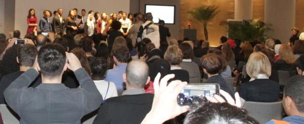 Eine Gruppe von Menschen steht auf einer Bühne vor einem Publikum.