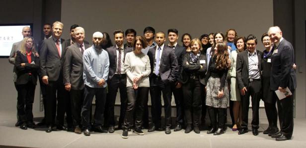 Eine Gruppe von Menschen posiert für ein Gruppenfoto auf einer Bühne.