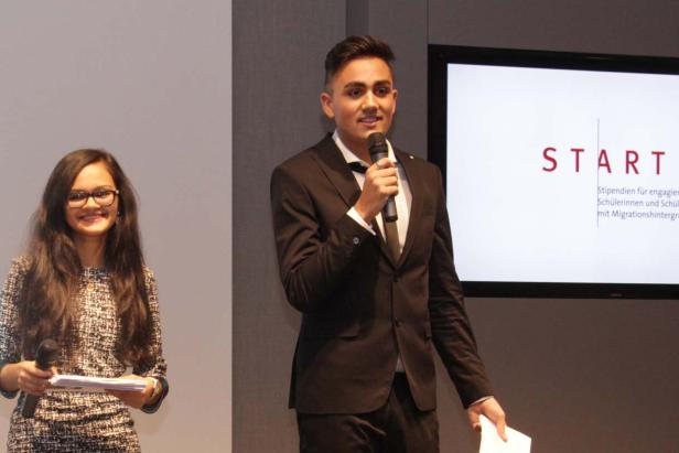 Ein junger Mann hält eine Rede mit Mikrofon, eine junge Frau steht daneben.