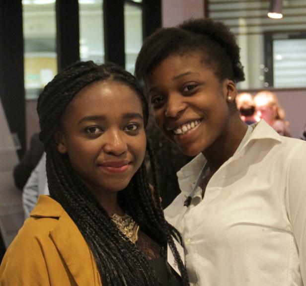 Zwei junge, lächelnde Frauen posieren für ein Foto.