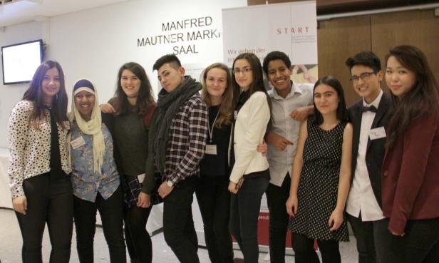Eine Gruppe junger Menschen posiert vor einem Banner des Manfred Mautner Markhof-Saals.