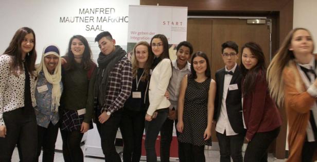 Eine Gruppe junger Menschen posiert vor einem Banner der Organisation START.