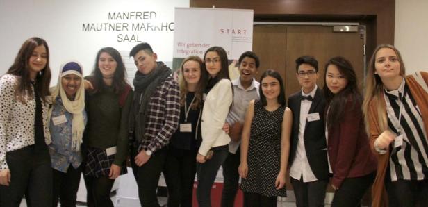 Eine Gruppe junger Menschen posiert vor einem Banner für eine Integrationsinitiative.