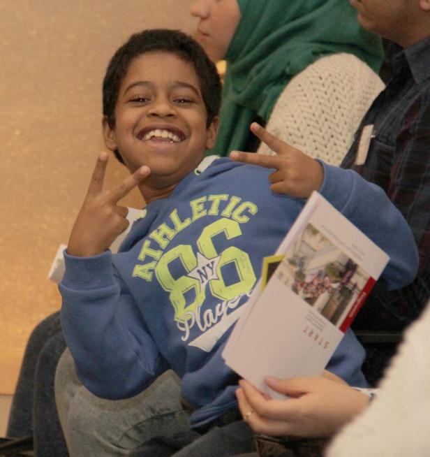 Ein lächelnder Junge zeigt mit beiden Händen das Victory-Zeichen.
