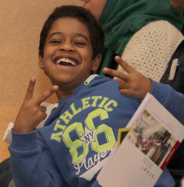 Ein lachender Junge zeigt mit beiden Händen das Victory-Zeichen.