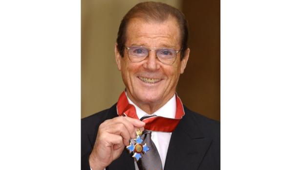 Roger Moore mit Brille und einer Auszeichnung am Band.