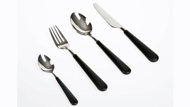 Ein Set aus Messer, Gabel, großem und kleinem Löffel mit schwarzen Griffen liegt auf einem weißen Hintergrund.