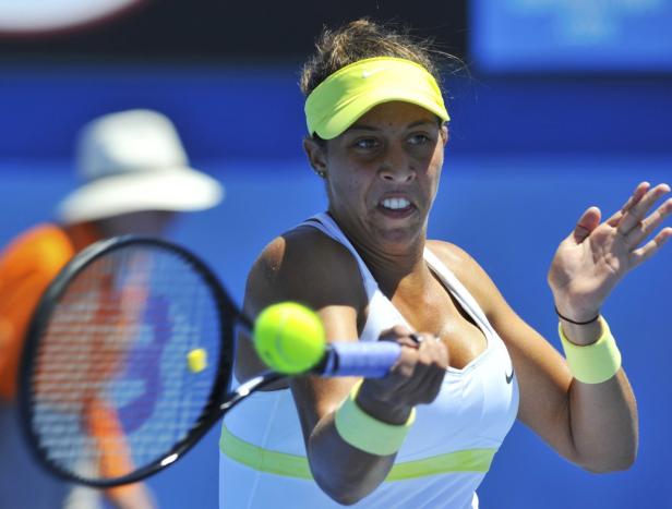 Eine Tennisspielerin schlägt einen Ball mit ihrem Schläger.