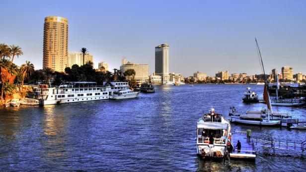 Blick auf den Nil in Kairo mit Booten und der Skyline im Hintergrund.