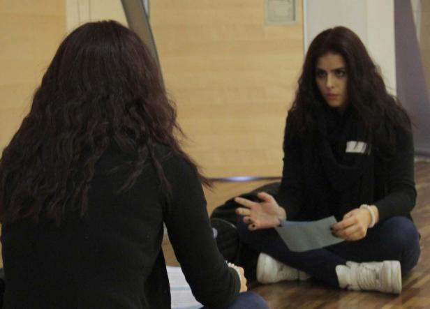 Zwei Frauen sitzen auf dem Boden und diskutieren miteinander.