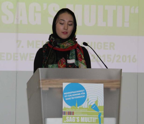 Eine junge Frau mit Kopftuch steht an einem Rednerpult bei einer Veranstaltung von „Sag’s Multi!“.
