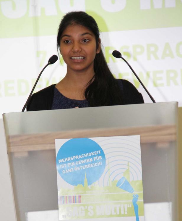 Eine junge Frau hält eine Rede auf einer Veranstaltung zum Thema Mehrsprachigkeit.