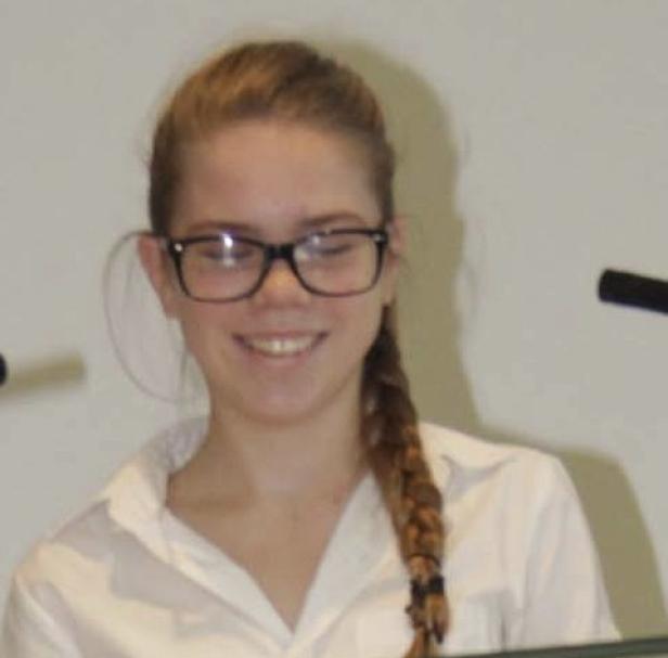 Ein lächelndes junges Mädchen mit Brille und Zopf.