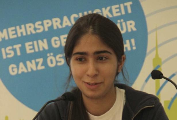 Eine junge Frau spricht bei einer Veranstaltung vor einem Mikrofon.