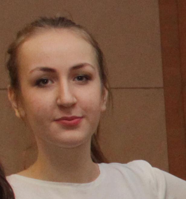 Eine junge Frau mit blonden Haaren und einem weißen T-Shirt blickt in die Kamera.