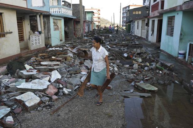 Eine Frau geht durch eine Straße voller Trümmer nach einem Sturm.